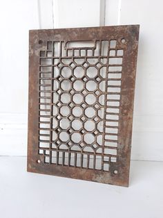 an old metal grate with holes in the center on a white background, hanging from a wall