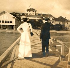 an old photo of two people standing on a pier