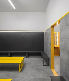 an empty room with benches and lockers on the walls, in grey and yellow colors