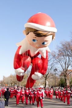 an inflatable santa clause balloon floats through the air as people walk by onlookers