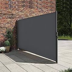 an open door on the side of a brick building with flowers in front of it