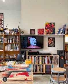 a living room filled with lots of books and furniture next to a flat screen tv