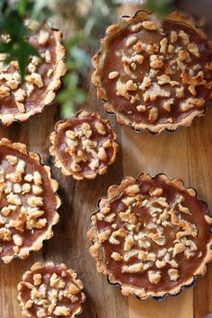 four pies with nuts on top sitting on a wooden table