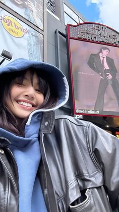 a woman standing in front of a building wearing a jacket and hat