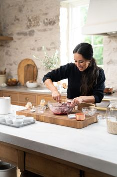 a woman preparing food on top of a wooden cutting board