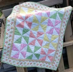 a quilted blanket sitting on top of a wooden bench next to a pile of wood