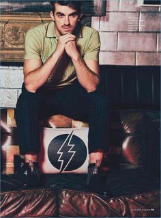 a man sitting on top of a leather couch next to a pillow with a lightning symbol