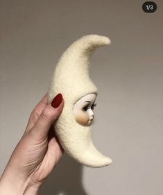 a hand holding a fake moon with a face on it