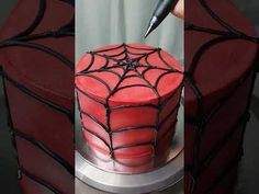 a spider - man cake is decorated with red frosting and black icing, along with a knife