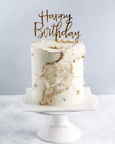 a birthday cake with white frosting and gold sprinkles that says happy birthday