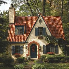 a white house with red tile roof and blue shutters in the front yard is surrounded by greenery