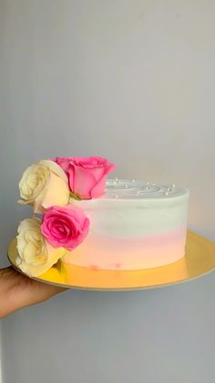 a hand holding a cake with flowers on it