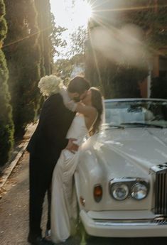 a bride and groom kissing next to a white car