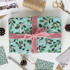 wrapping paper wrapped in blue with pink ribbon and pine cones