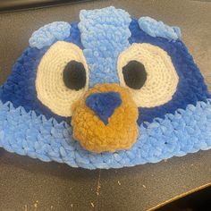 a crocheted blue bird hat sitting on top of a table