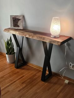 a wooden table sitting on top of a hard wood floor next to a planter