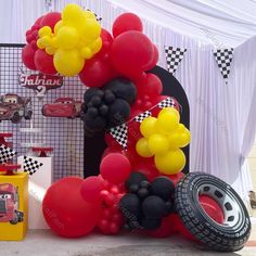 the balloon arch is decorated with cars and balloons