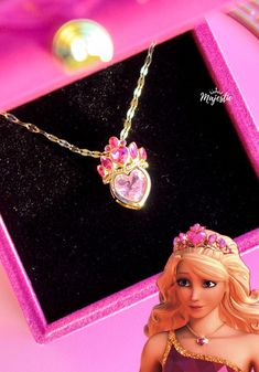 a barbie doll wearing a tiara and necklace in a pink box with a gold chain