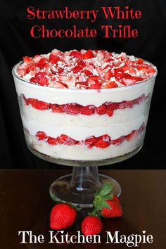 strawberry white chocolate trifle in a glass dish with strawberries on the side and text overlay