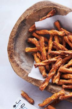 a wooden bowl filled with french fries on top of a table