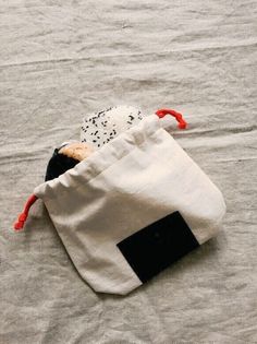 a small white bag sitting on top of a bed next to a black and white pillow