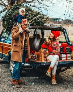 a man and woman are sitting in the back of a car with their dog,