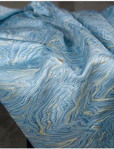 a blue and gold marbled fabric on top of a metal table