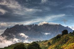 the mountains are covered in clouds and trees