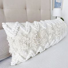 a white pillow sitting on top of a bed next to a beige headboard and pillows