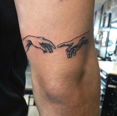 two hands touching each other with the creation behind them tattooed on both arm and leg