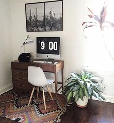 a room with a desk, chair and potted plant