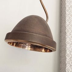 a lamp hanging from the side of a wall next to a window with curtains behind it