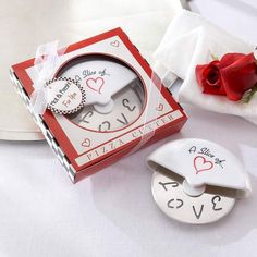 a red and white clock sitting on top of a table next to a box with a rose