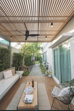 an outdoor living area with couches, tables and plants on the side of it