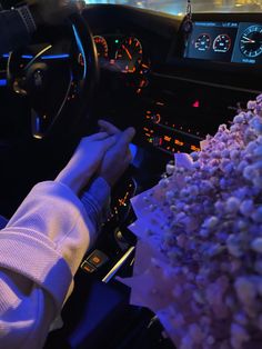 a person driving a car with popcorn on the dashboard and in front of him is a large bouquet of flowers