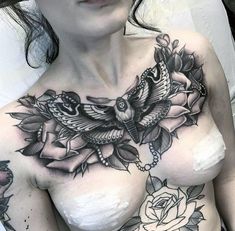 a woman with tattoos on her chest is posing for the camera and has flowers around her breast