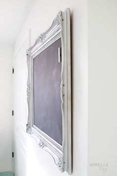 a chalkboard mounted to the wall in a room with white walls and green flooring