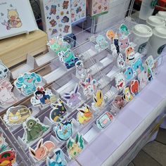 a table topped with lots of cartoon magnets on top of plastic trays next to each other