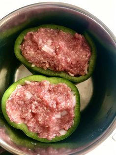 two green peppers filled with meat in a pot