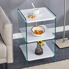 a three tiered glass shelf with plates and bowls on it, next to a chair