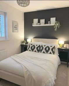 a white bed sitting in a bedroom next to two lamps on either side of the bed