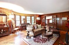 a living room with wood paneling and furniture in the middle of it, along with a piano