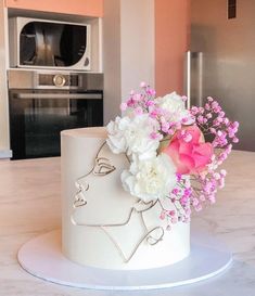 a white cake with pink and white flowers on the top is sitting on a table