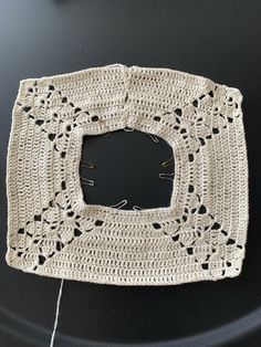 a crocheted square is sitting on a black surface