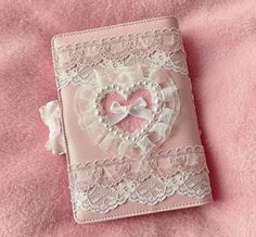 a small pink book with a heart on the front and white lace around the edges