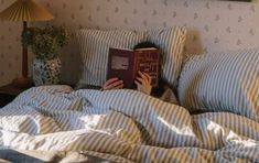 a person laying in bed with a book on their head and the covers pulled back