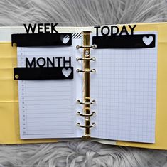 an open planner book with black and white stickers on the pages that read, week, month