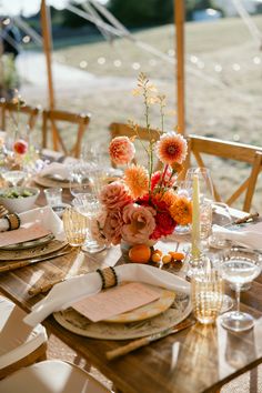 an outdoor table set with place settings and flowers