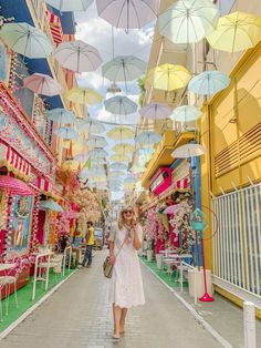 a woman is walking down the street under umbrellas