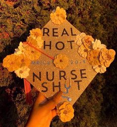 a hand holding a graduation cap with flowers on it that reads real hot nurse stuff